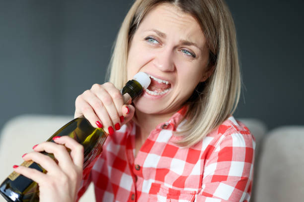 DrDalmao-Woman opens bottle of champagne with her teeth. Female alcoholism concept