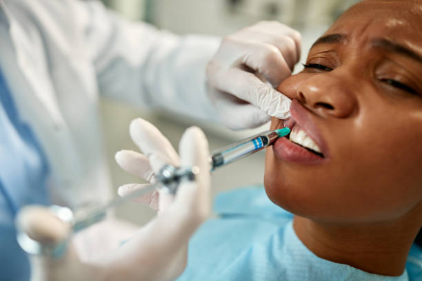 DrDalmao-Close-up of black woman getting anesthetic during dental procedure at dentist's office.